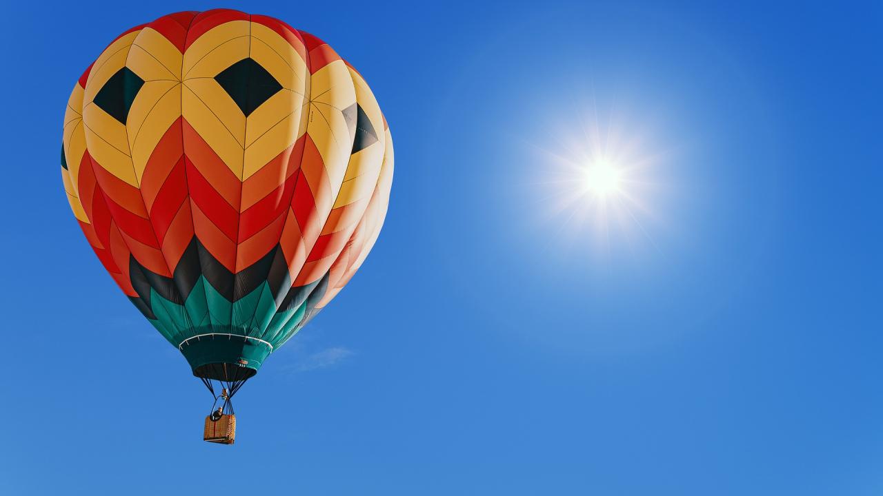 Stimmungsbild zum Beitrag: Es wird ein bunter Heißluftballon vor blauem Himmel abgebildet.