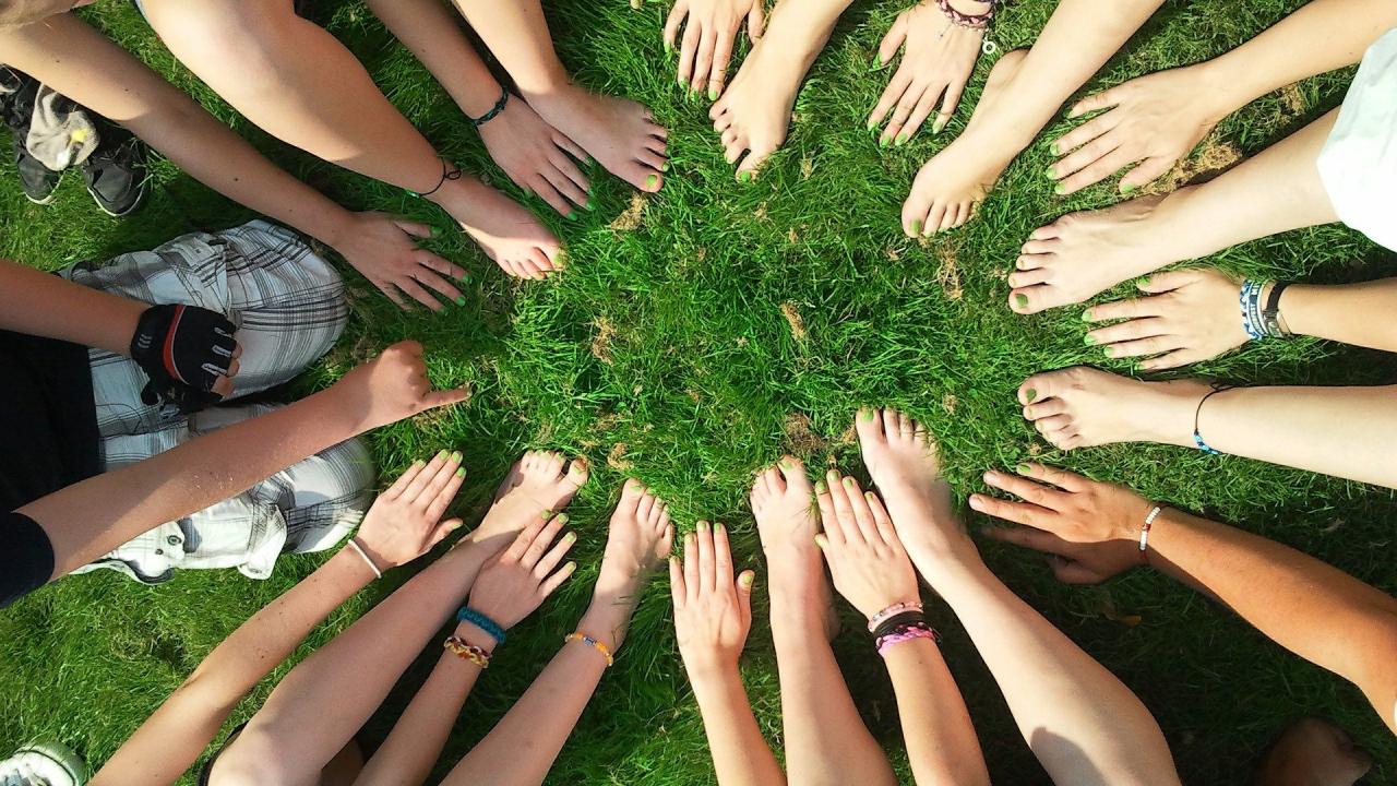 Stimmungsbild zum Beitrag: Es werden Hände und Füße, die im Kreis angeordnet sind auf einer Rasenfläche abgebildet.