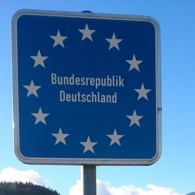 Stimmungsbild zum Beitrag: Es wird ein Straßenschild mit der Aufschrift "Bundesrepublik Deutschland" mit 12 Sternen, die kreisförmig angeordnet sind, abgebildet.