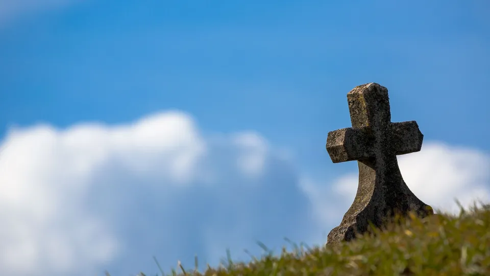 Stimmungsbild zum Beitrag: Es wird ein Grabstein auf einer Wiese abgebildet.