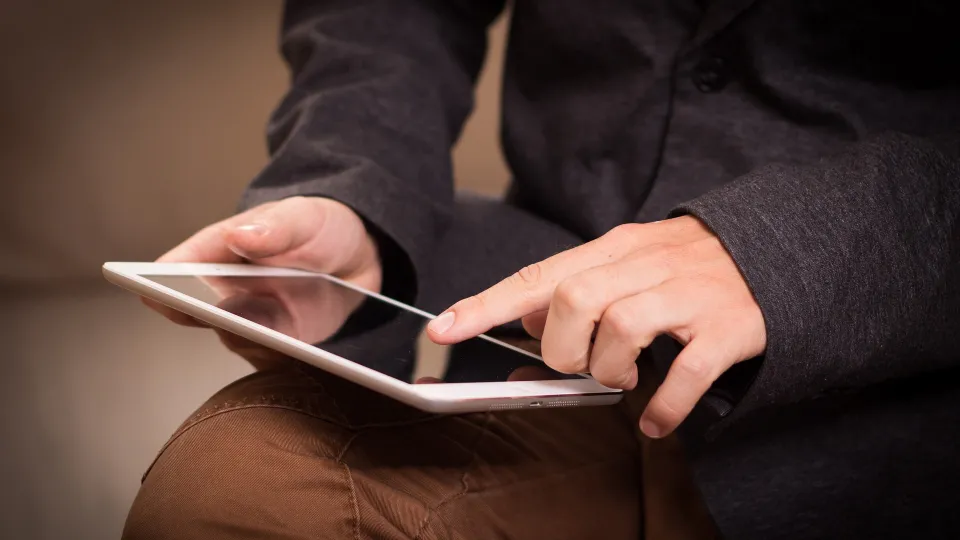 Stimmungsbild zum Beitrag: Es wird ein Mann mit einem Tablet in der Hand abgebildet.