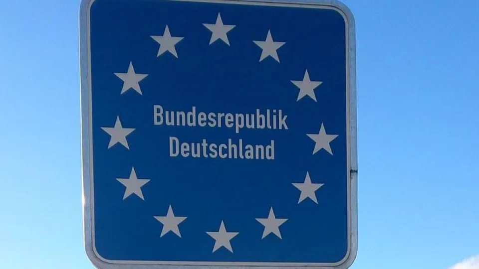 Stimmungsbild zum Beitrag: Es wird ein Straßenschild mit der Aufschrift "Bundesrepublik Deutschland" mit 12 Sternen, die kreisförmig angeordnet sind, abgebildet.